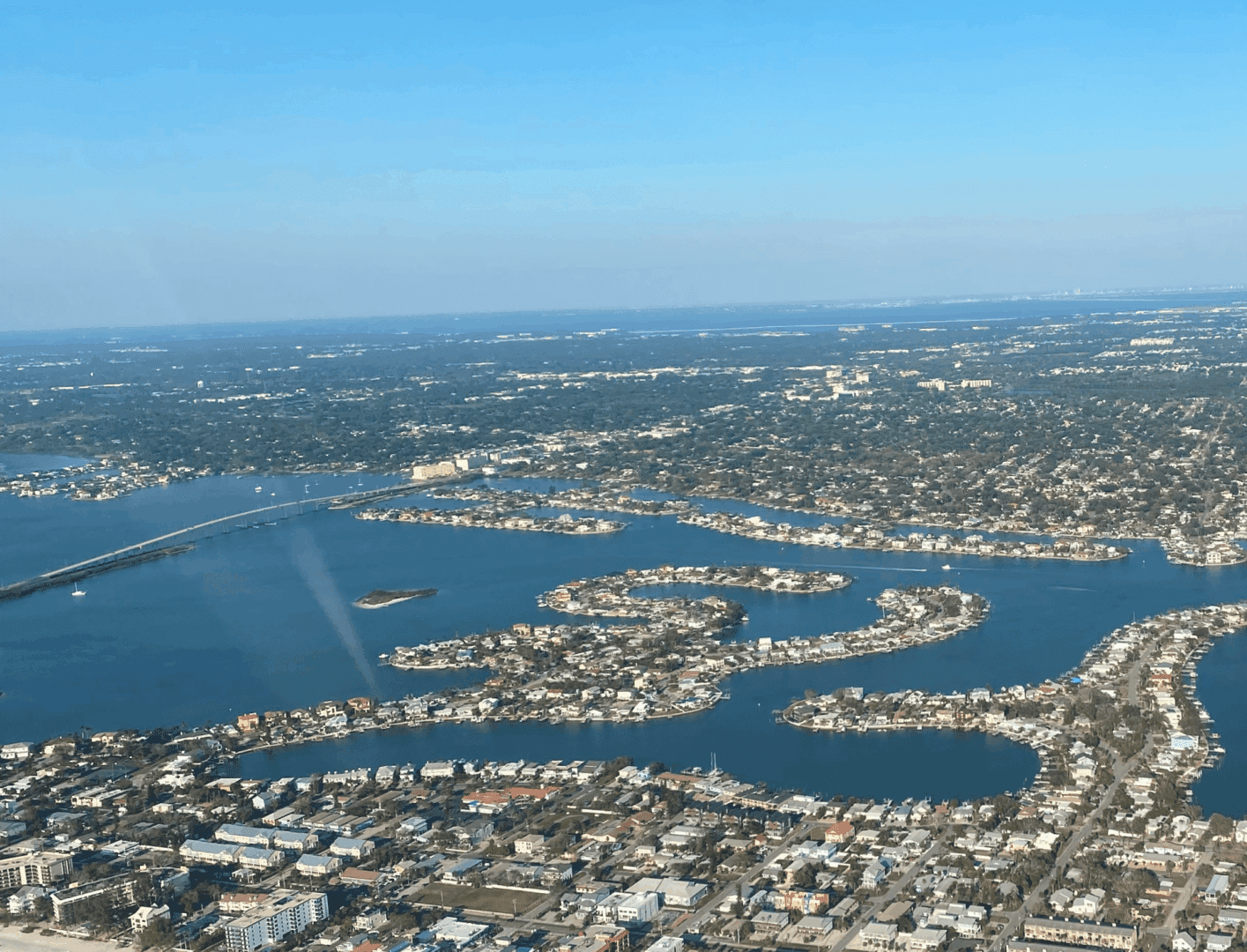 Aerial view of a coastal city with waterways and a clear sky.